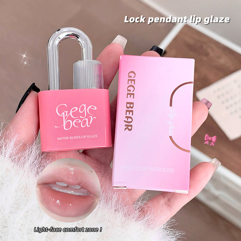 Pink lock-shaped lip gloss with packaging held by a hand, on a neutral background.