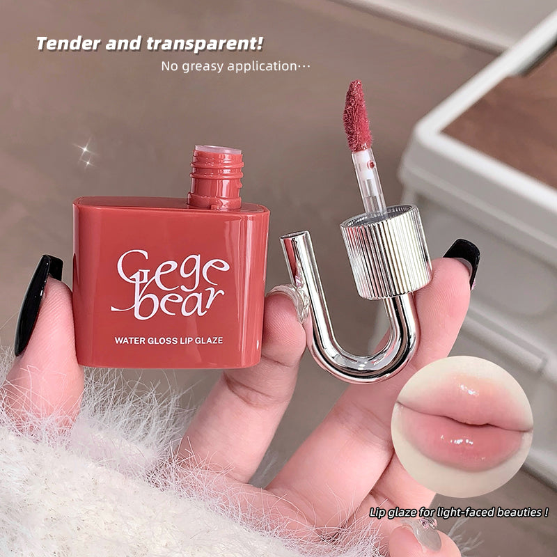 Gege bear water gloss lip glaze held by a hand with a blurred background
