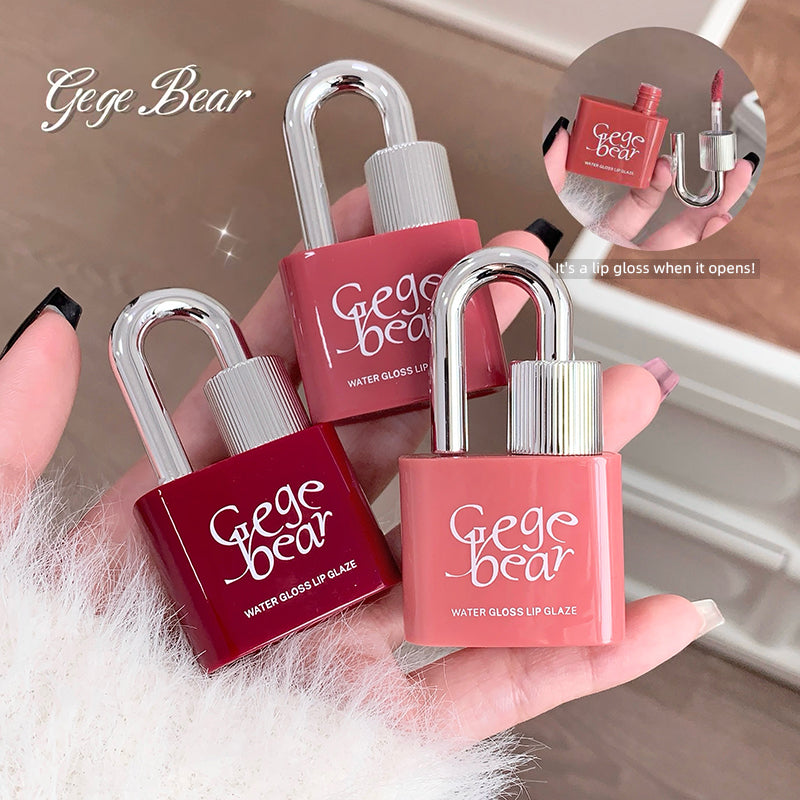 Gege Bear lip gloss glaze in lock-shaped packaging held by a hand.